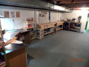 Completed walls with new bench top height electrical outlets, pegboard, and work benches and storage shelves.